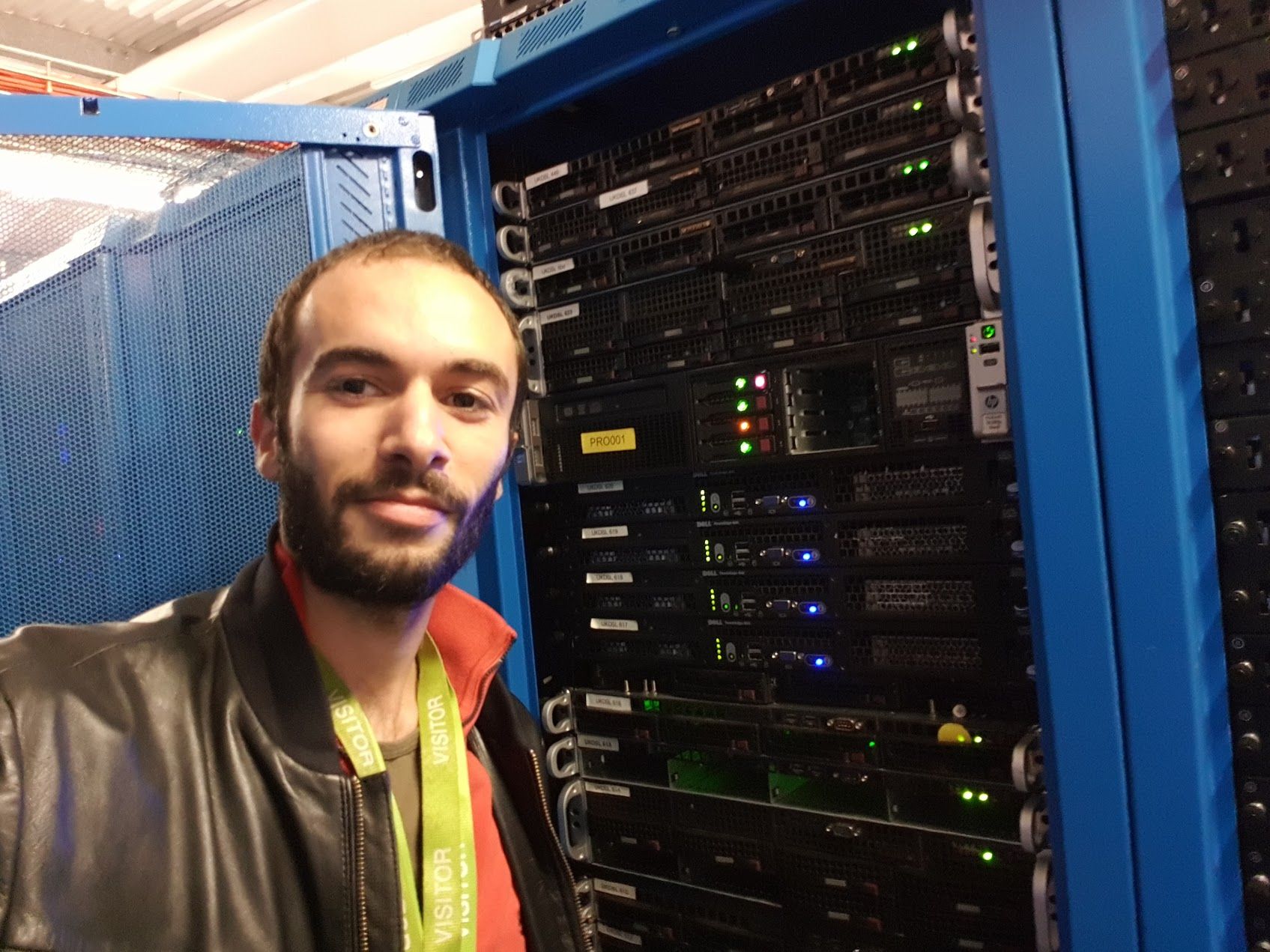 Selfie in a data centre next to a blue-framed rack of labelled HP and Dell servers