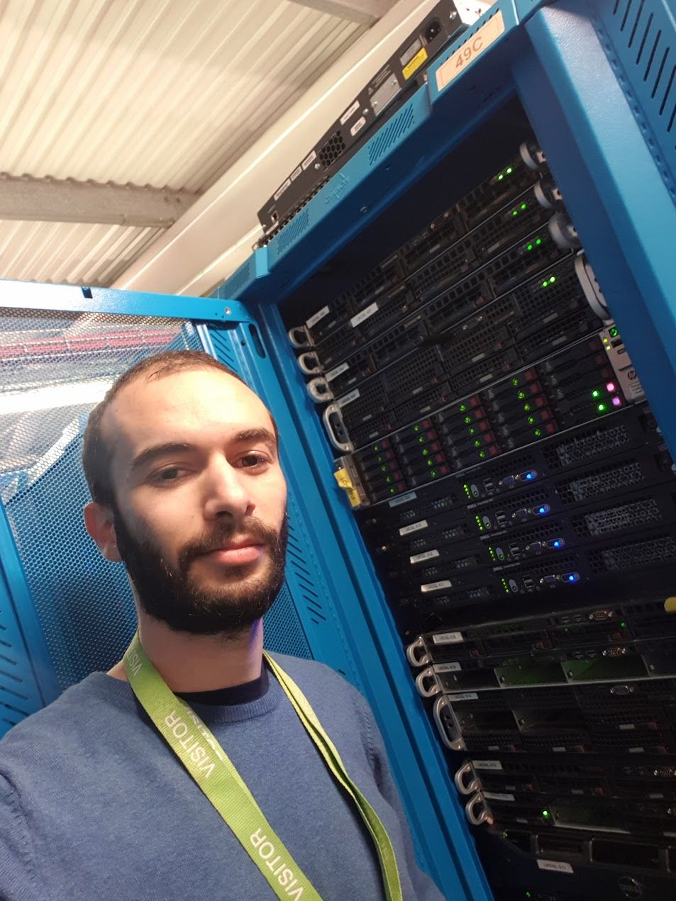 Selfie next to a denser rack of rack-mount servers with green activity LEDs